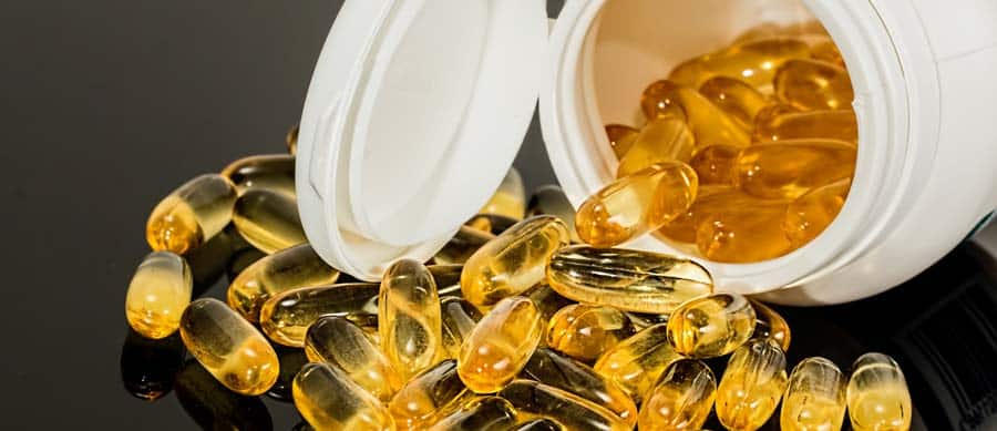 Yellow OTC supplements spilling from a white container, sometimes used during alcohol detox or for managing alcohol withdrawal symptoms.