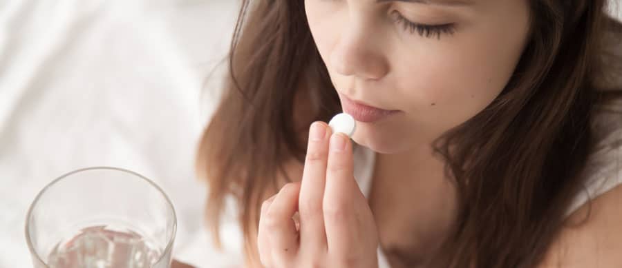 A close-up of a young adult taking a single pill—symbolizing the risk of dependency on anxiety medication like benzodiazepines.