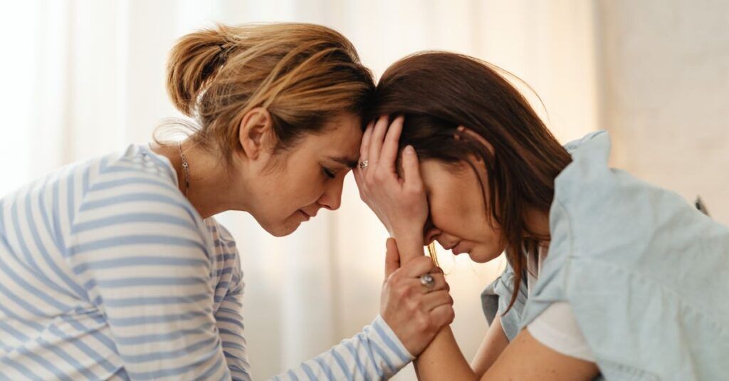 Two women comfort each other in a moment of emotional support indoors.