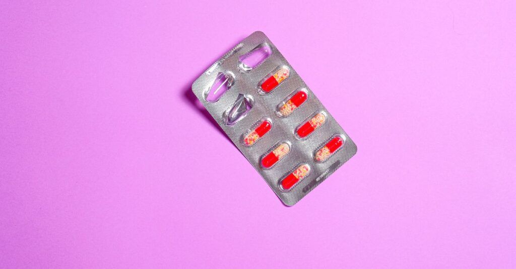 Close-up of a blister pack containing red capsules on a vibrant purple background.